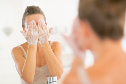 Young woman washing face in bathroom