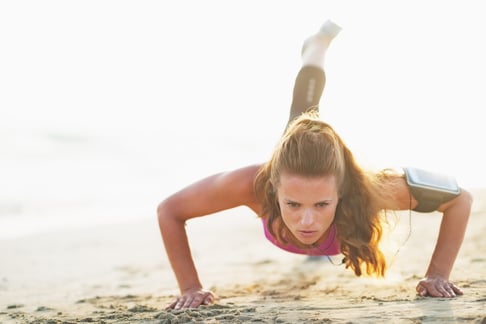 Female athlete doing push ups on beach