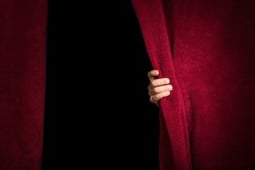 Hand appearing beneath the curtain.
