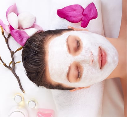 Young beautiful girl receiving pink facial mask